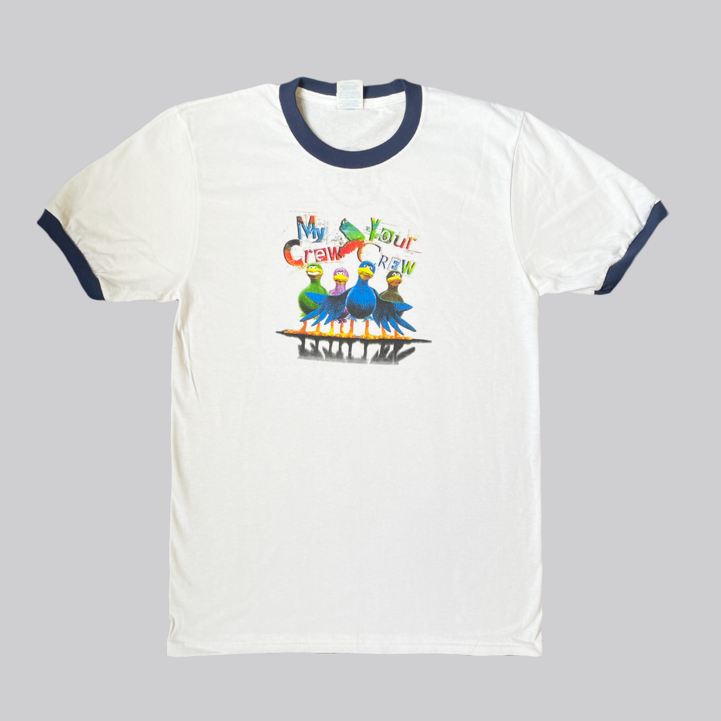 A classic white cotton-ringer tee with navy ribbed trim on the neckline and sleeves. The front features a colorful graphic of lpt mascot Larry Bird with his wings spread, surrounded by his crew, with their reflections visible below. Above the birds, the text “MY CREW – YOUR CREW” is displayed in vibrant color and varied fonts. On the back, near the top just under the neckline, is the LPT circle logo.