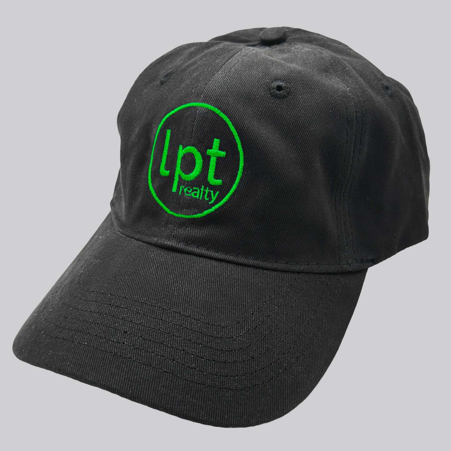 A black twill cap with a relaxed fit, matching stitching, and embroidered eyelets. The front panels feature the “lpt realty” circle logo embroidered in contrasting neon green. 