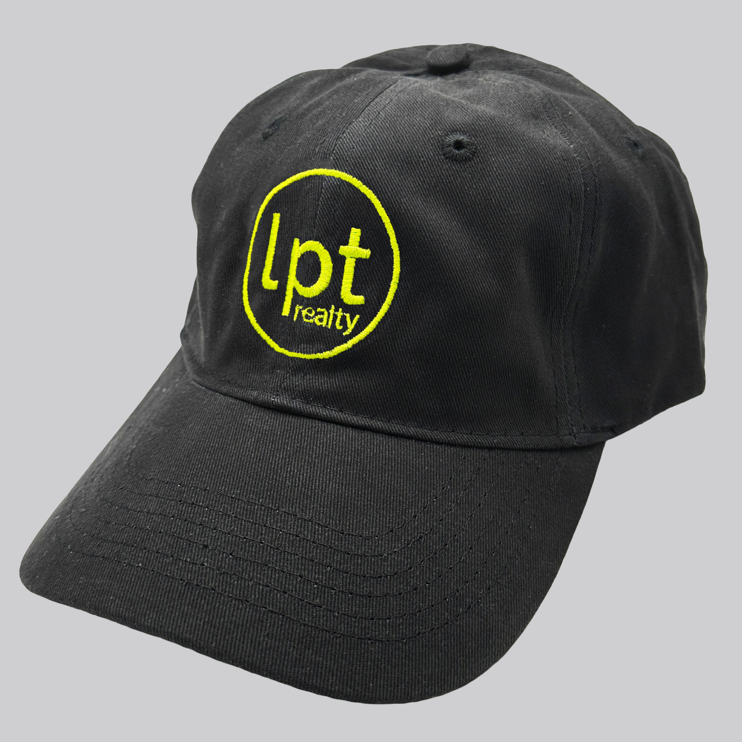 A black twill cap with a relaxed fit, matching stitching, and embroidered eyelets. The front panels feature the “lpt realty” circle logo embroidered in contrasting bright yellow. 