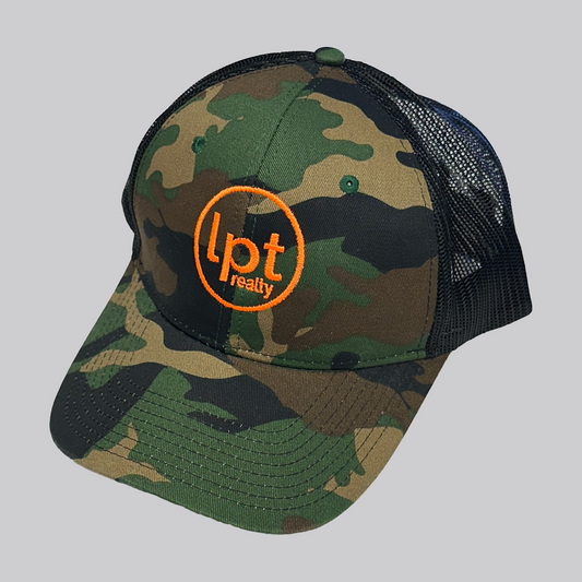 Classic trucker hat design with solid front panels and black mesh back. The front panels and bill are a black/green/khaki/brown camo pattern with an embroidered orange “Lpt Realty” circle logo at the center. 