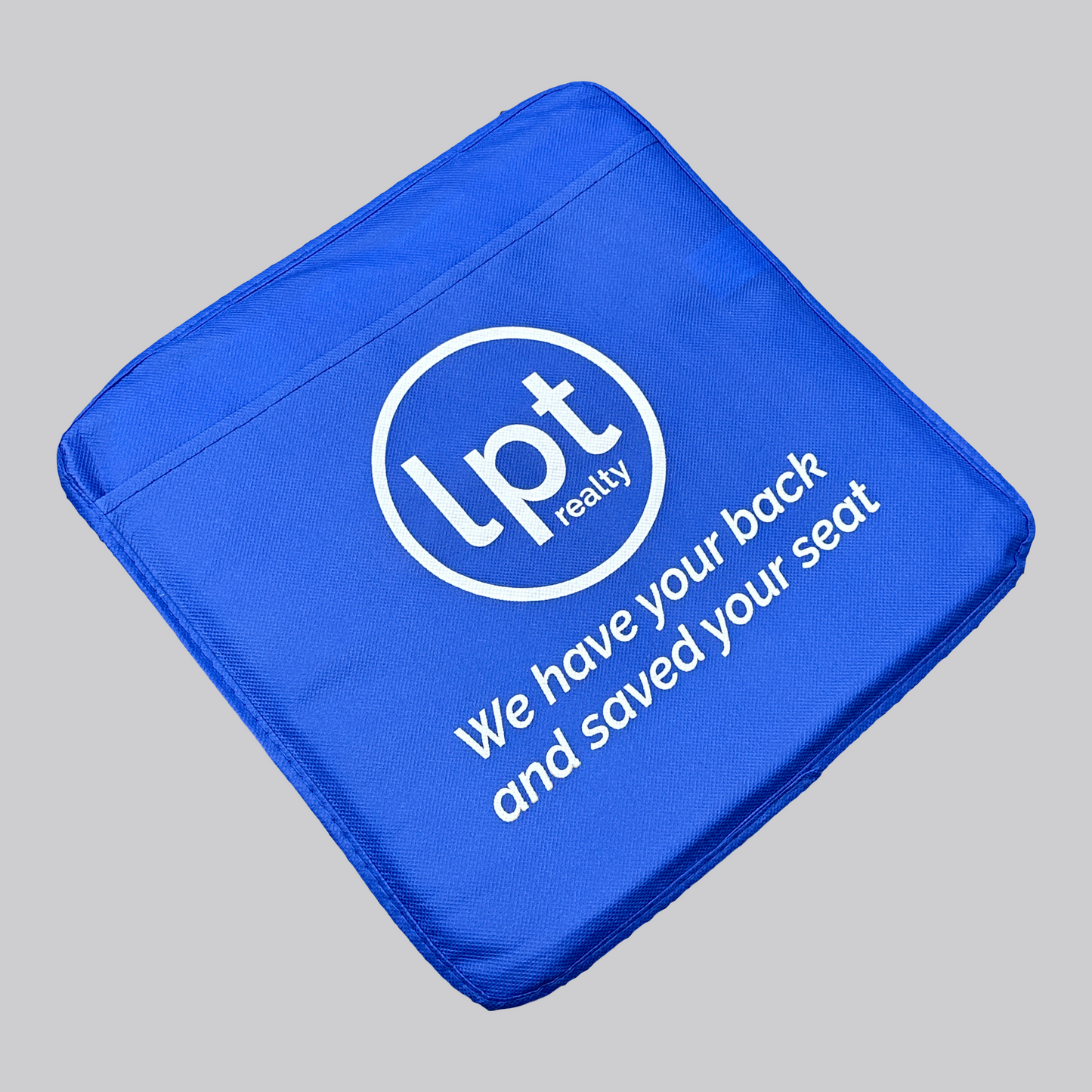 A square seat cushion in bright royal blue. The front features a full-panel pocket and a prominent white LPT realty circle logo. Under the logo, white text reads: “We have your back and saved your seat”.