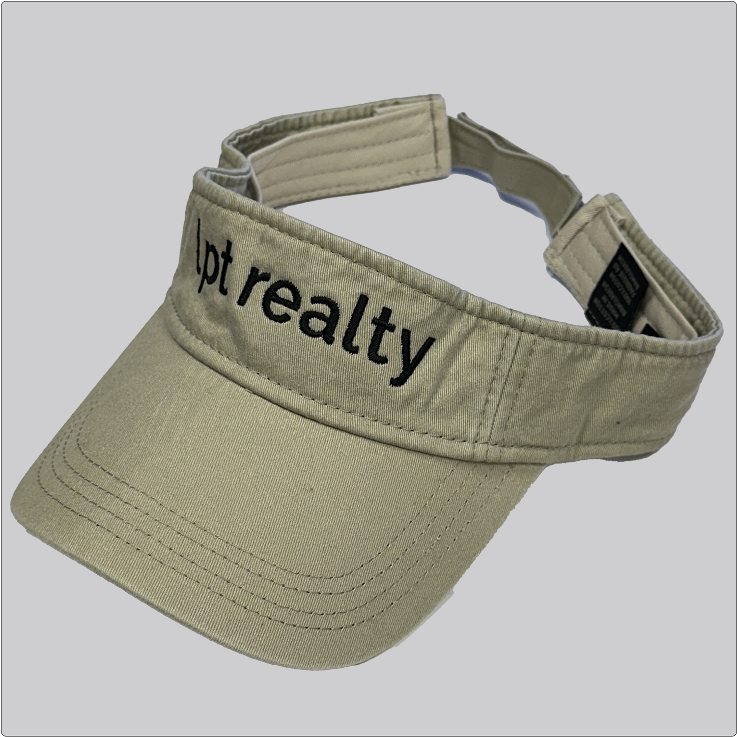 A casual, washed denim visor in khaki with “lpt realty” embroidered in a contrasting dark color across the crown. 