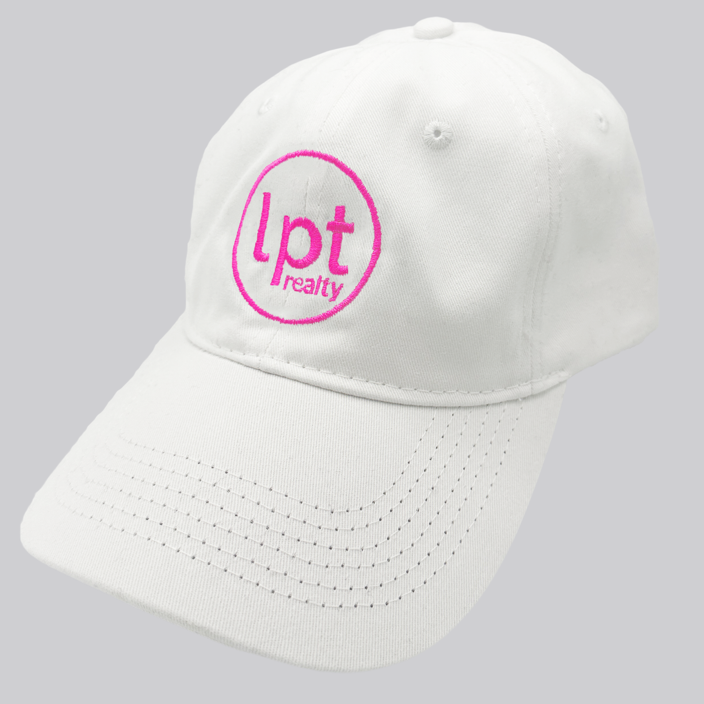 A white twill cap with a relaxed fit, matching stitching, and embroidered eyelets. The front panels feature the “lpt realty” circle logo embroidered in hot pink.  